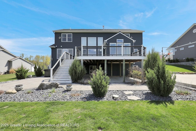 rear view of property featuring stairway, a yard, and a deck