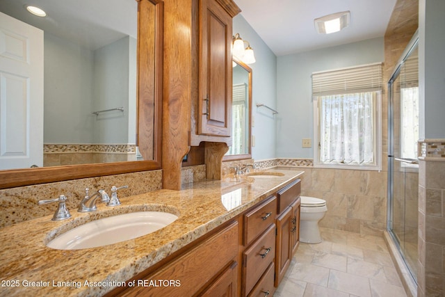 3796 Viceroy Dr, Okemos, MI 48864 - full bath featuring tile walls, a stall shower, toilet, double vanity, and a wainscoted wall