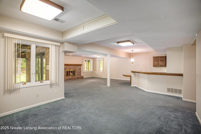 3796 Viceroy Dr, Okemos, MI 48864 - basement with dark carpet, baseboards, a fireplace, and a textured ceiling