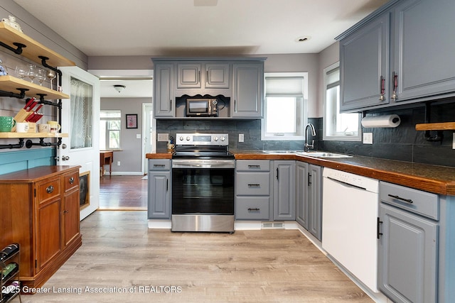kitchen featuring dark countertops, stainless steel electric stove, light wood-style flooring, dishwasher, and gray cabinetry