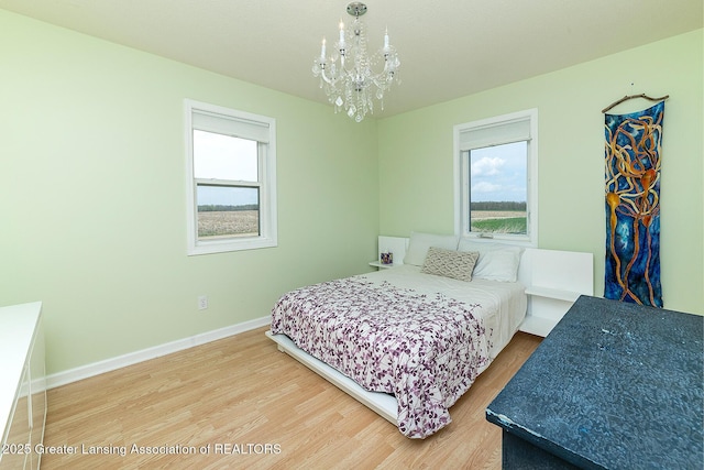 bedroom with baseboards, wood finished floors, and a notable chandelier