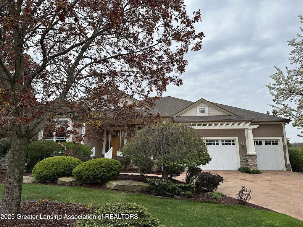 view of front of home with a garage, a shingled roof, stone siding, and concrete driveway