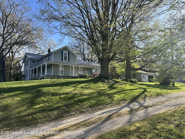 view of front facade with covered porch, a chimney, and a front lawn