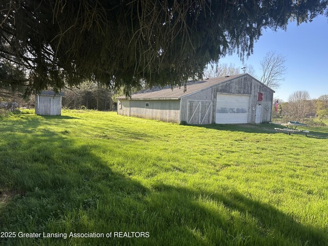 view of yard with a detached garage, an outbuilding, and an outdoor structure