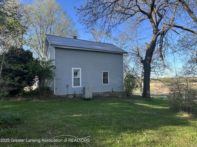 view of property exterior with a yard, central AC, and metal roof