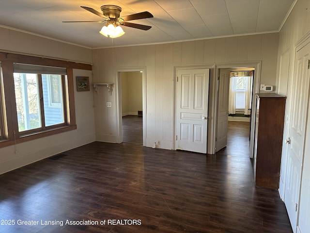 unfurnished room featuring crown molding, dark wood-style flooring, ceiling fan, and baseboards