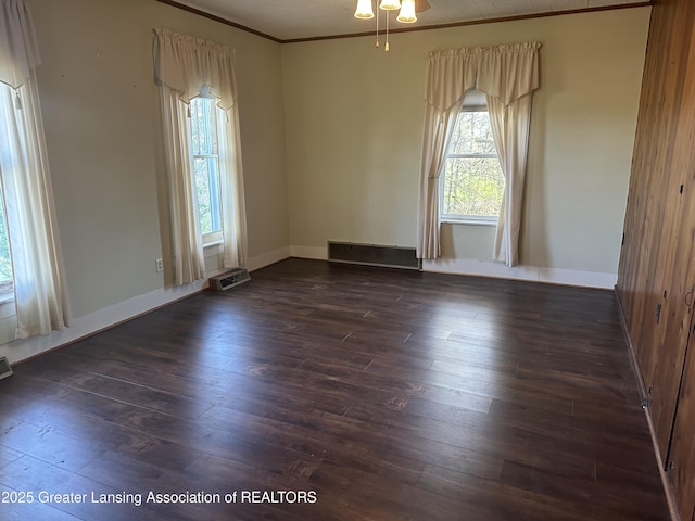 unfurnished room featuring crown molding, a ceiling fan, baseboards, dark wood-type flooring, and visible vents