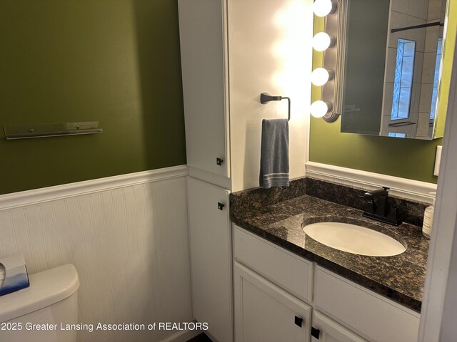 bathroom with vanity, wainscoting, and toilet