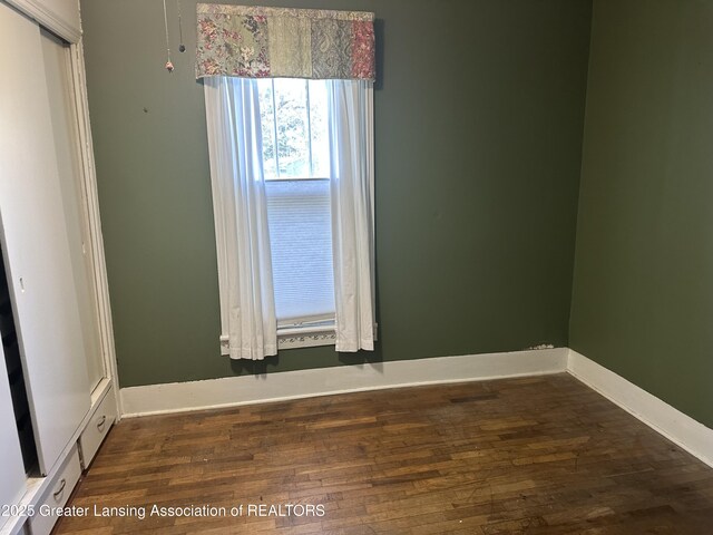spare room with baseboards and wood finished floors