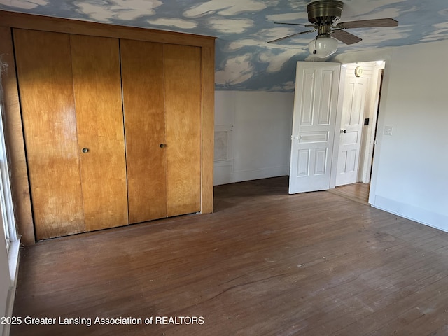 unfurnished bedroom featuring baseboards, wood finished floors, and a closet