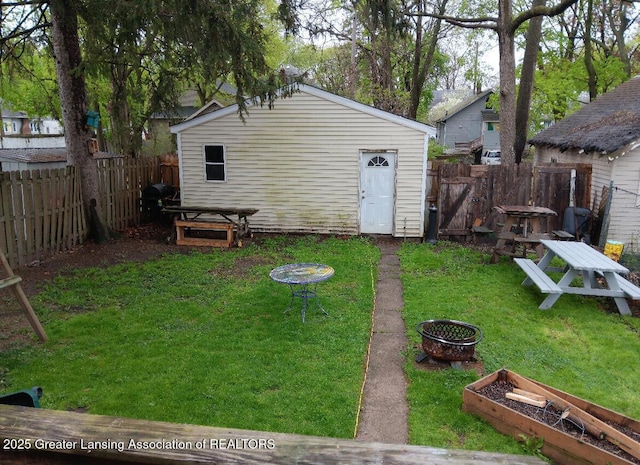 exterior space with an outdoor structure, a fire pit, a garden, and a fenced backyard