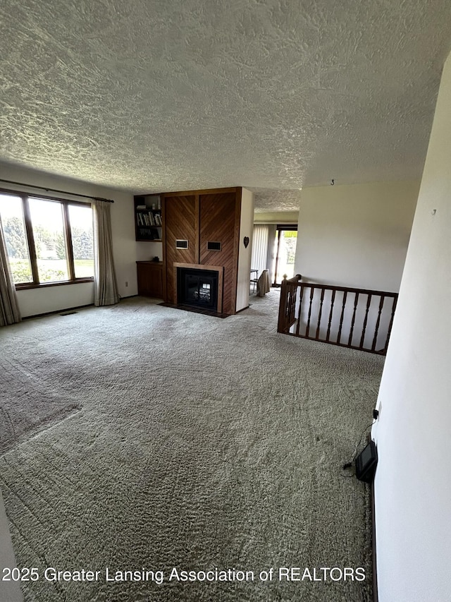 9466 W Grand River Ave, Grand Ledge, MI 48837 - unfurnished living room featuring carpet floors, a textured ceiling, and a large fireplace