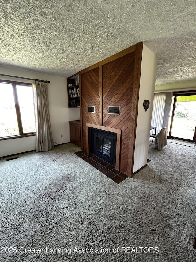 9466 W Grand River Ave, Grand Ledge, MI 48837 - unfurnished living room with visible vents, a textured ceiling, a fireplace with flush hearth, and carpet