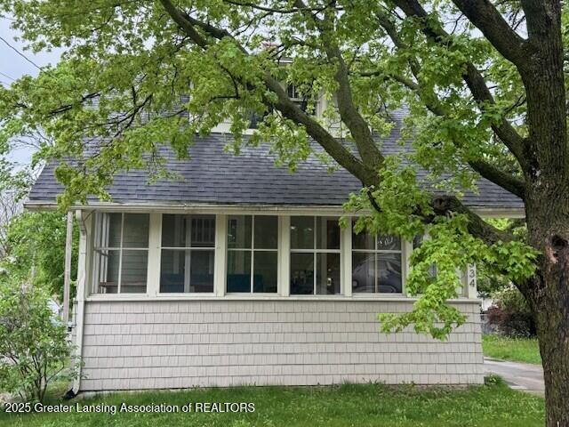 view of side of property featuring roof with shingles and a sunroom