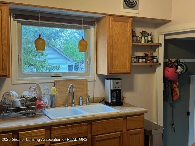 kitchen with a sink, brown cabinets, open shelves, and light countertops
