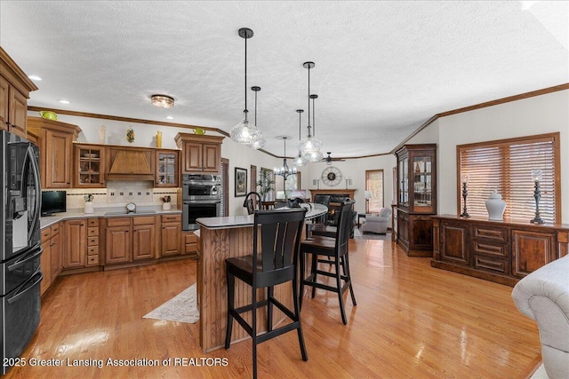 3012 Appaloosa Way, Lansing, MI 48906 - kitchen featuring a textured ceiling, open floor plan, light wood-type flooring, a kitchen bar, and black appliances