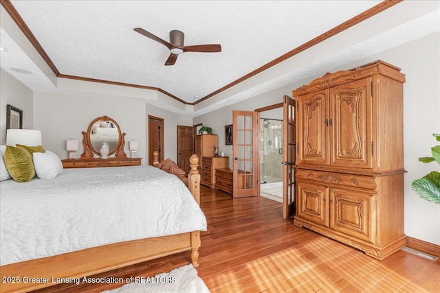 3012 Appaloosa Way, Lansing, MI 48906 - bedroom with crown molding, a textured ceiling, french doors, light wood-type flooring, and a tray ceiling
