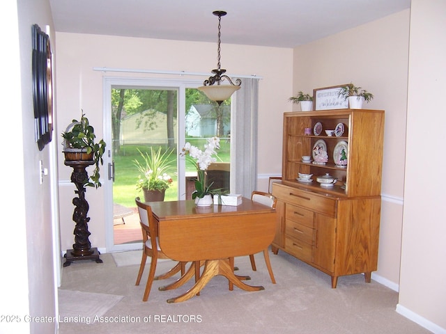dining area featuring baseboards, a chandelier, and light carpet
