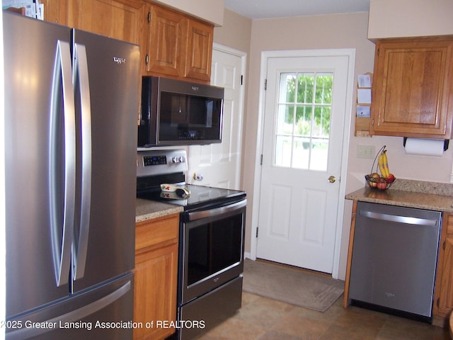 kitchen with appliances with stainless steel finishes, brown cabinets, and light stone counters