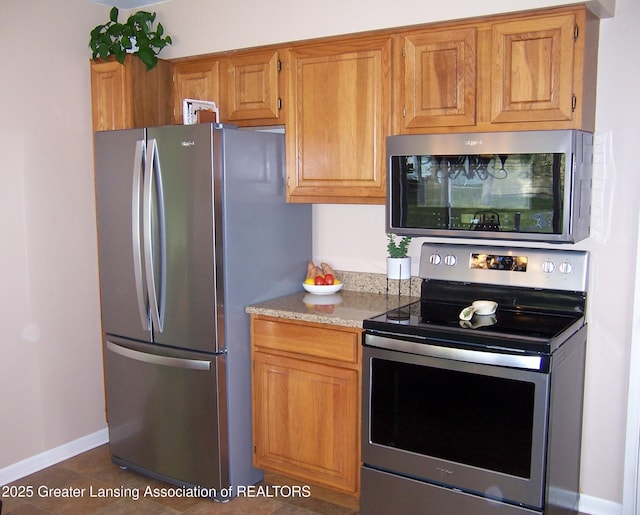 kitchen featuring light stone counters, brown cabinetry, and stainless steel appliances