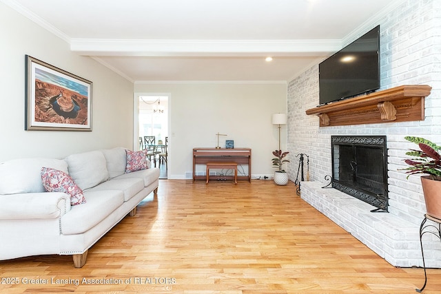 living room with light wood-style floors, ornamental molding, a brick fireplace, and baseboards