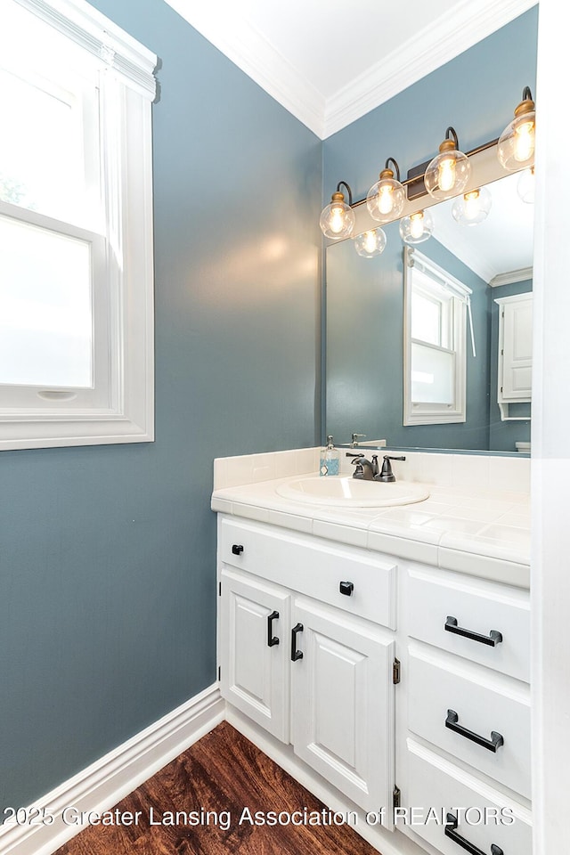 bathroom featuring crown molding, vanity, wood finished floors, and baseboards