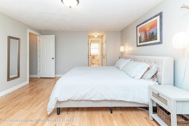 bedroom featuring light wood finished floors, baseboards, and ensuite bath