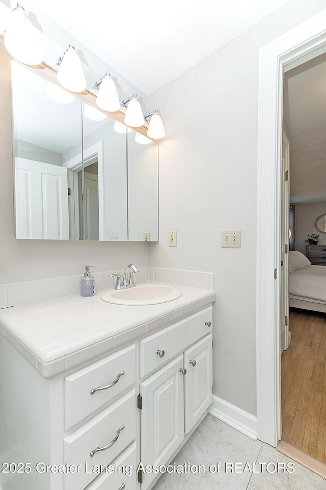 bathroom with vanity, baseboards, and ensuite bathroom