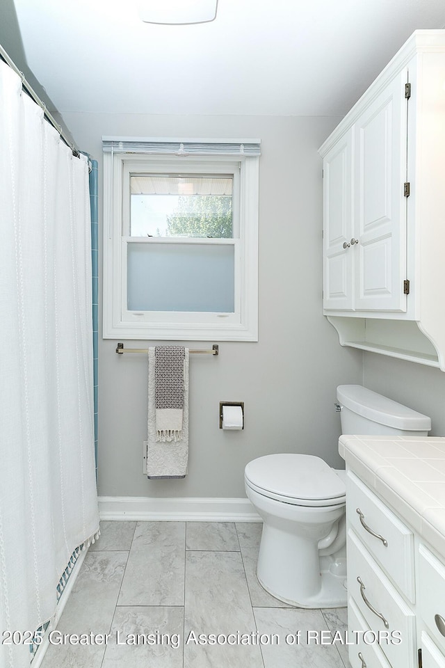 full bathroom featuring baseboards, toilet, and vanity