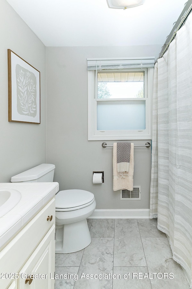 bathroom featuring toilet, vanity, baseboards, and marble finish flooring