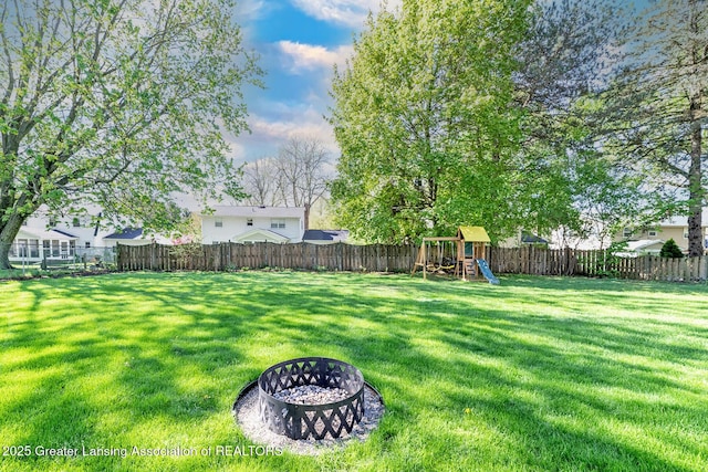 view of yard featuring a playground and an outdoor fire pit
