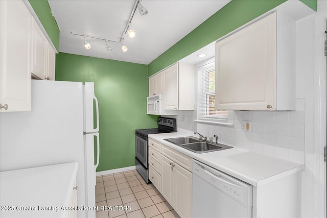 kitchen with a sink, light countertops, light tile patterned floors, white appliances, and white cabinetry