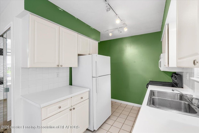 kitchen featuring freestanding refrigerator, electric range, white cabinets, tasteful backsplash, and a sink