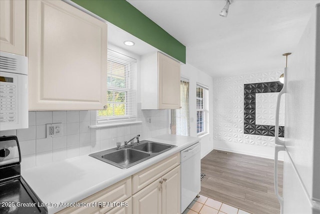 kitchen featuring a sink, white appliances, light countertops, baseboards, and light tile patterned floors