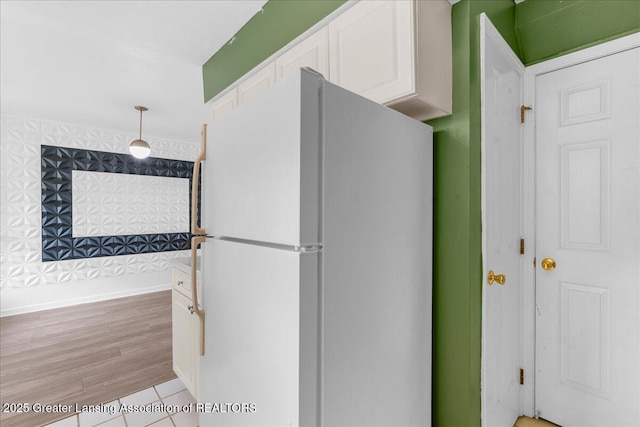 kitchen with freestanding refrigerator, light wood-type flooring, white cabinetry, and decorative light fixtures