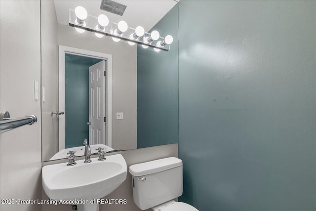 half bathroom featuring toilet, visible vents, and a sink