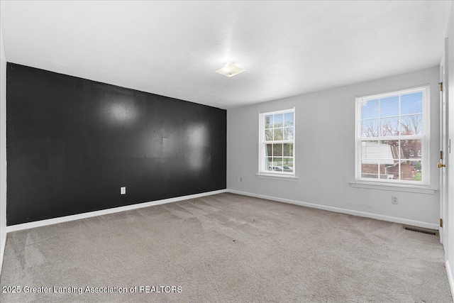 empty room featuring carpet flooring, baseboards, and visible vents