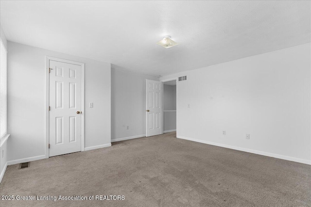 unfurnished bedroom featuring baseboards, carpet flooring, and visible vents