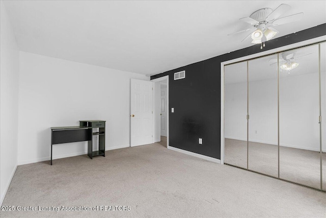 unfurnished bedroom featuring carpet floors, visible vents, a closet, baseboards, and ceiling fan
