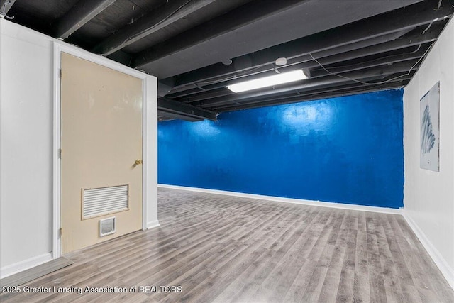 finished below grade area featuring baseboards and wood finished floors