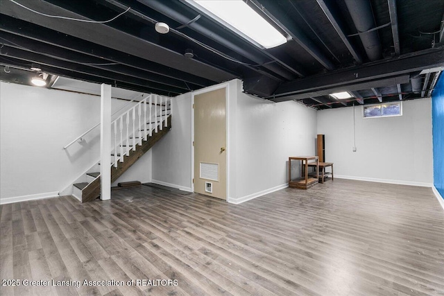 below grade area with stairway, baseboards, wood finished floors, and visible vents