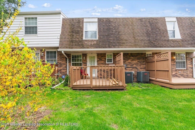 rear view of property featuring brick siding, a shingled roof, mansard roof, and a deck