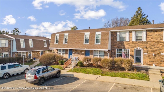 multi unit property with brick siding and uncovered parking