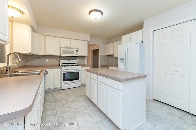 kitchen with white appliances, white cabinets, a sink, and a center island