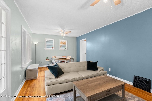 living area with baseboards, light wood finished floors, and ceiling fan