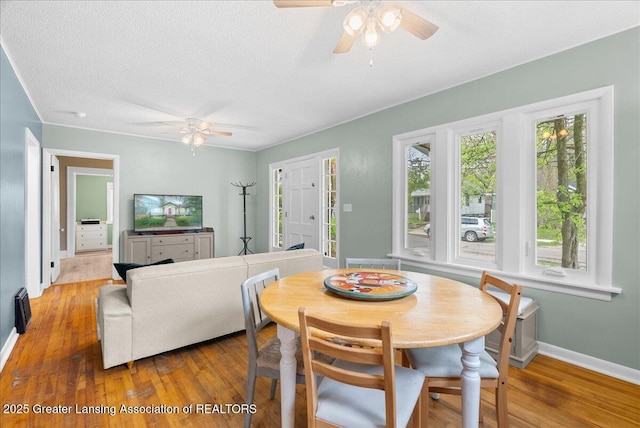 dining area featuring wood-type flooring, a textured ceiling, ceiling fan, and baseboards