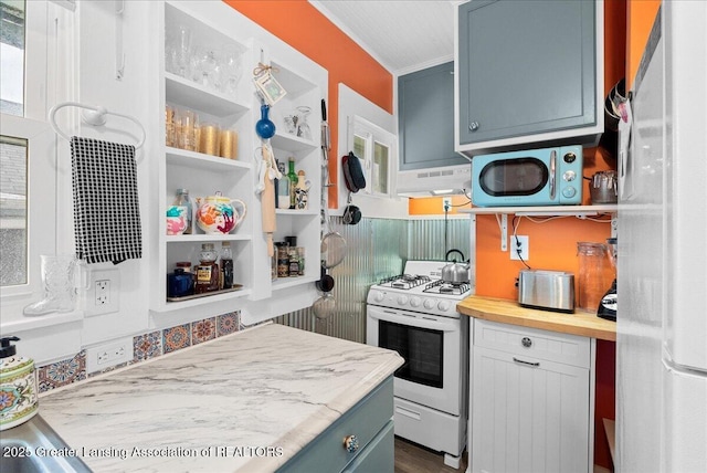 kitchen with a toaster, white appliances, butcher block countertops, under cabinet range hood, and blue cabinets