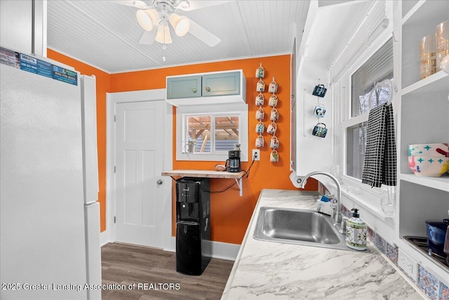 kitchen with ceiling fan, a sink, freestanding refrigerator, baseboards, and wood finished floors