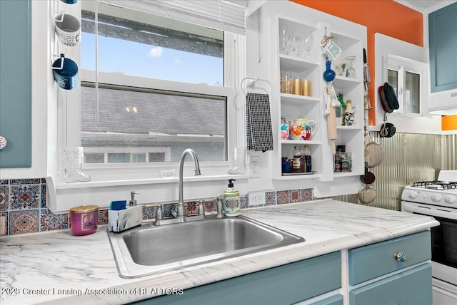 kitchen featuring light countertops, blue cabinetry, a sink, and white gas range