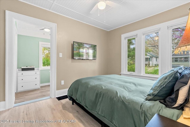 bedroom featuring baseboards, multiple windows, and light wood-type flooring